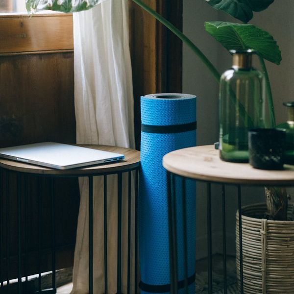 Cozy corner of a room with a yoga mat and a plant.